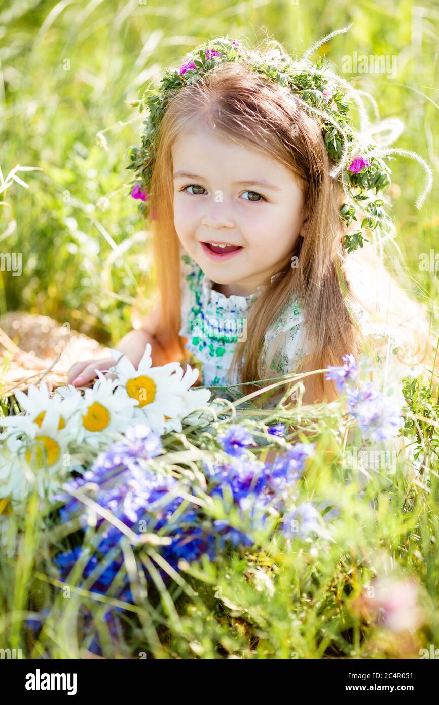 portrait of a cute little girl with a wreath on her head smiling ...