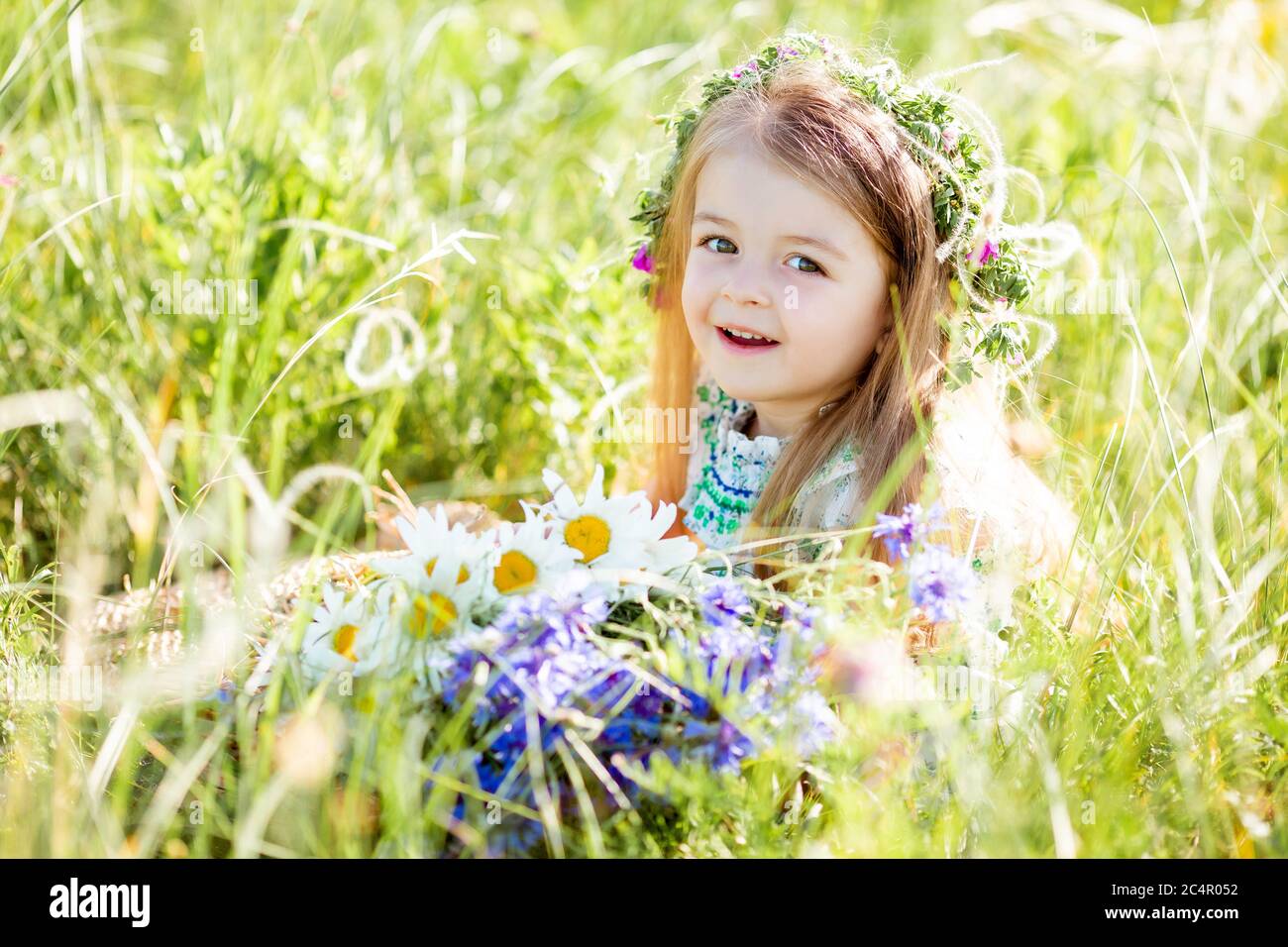 portrait of a cute little girl with a wreath on her head smiling ...