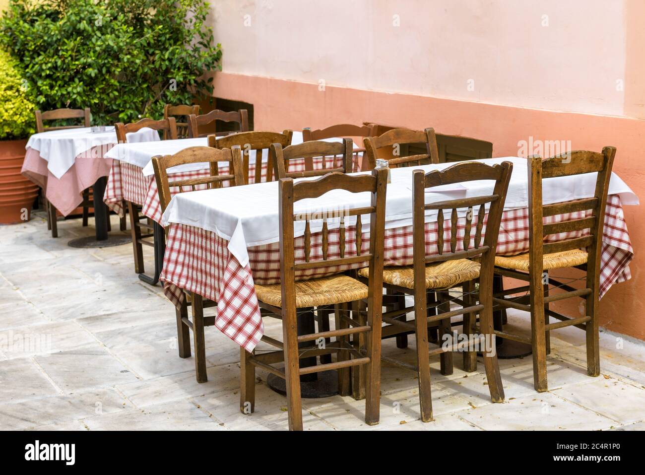 Street cafe with plants in Plaka district, Athens, Greece. Traditional Greek cafe for tourists in Athens. Restaurant tables outdoor in Athens center. Stock Photo