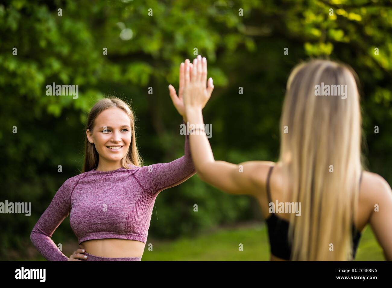 Two young sporty women giving each other a high five before workout ...