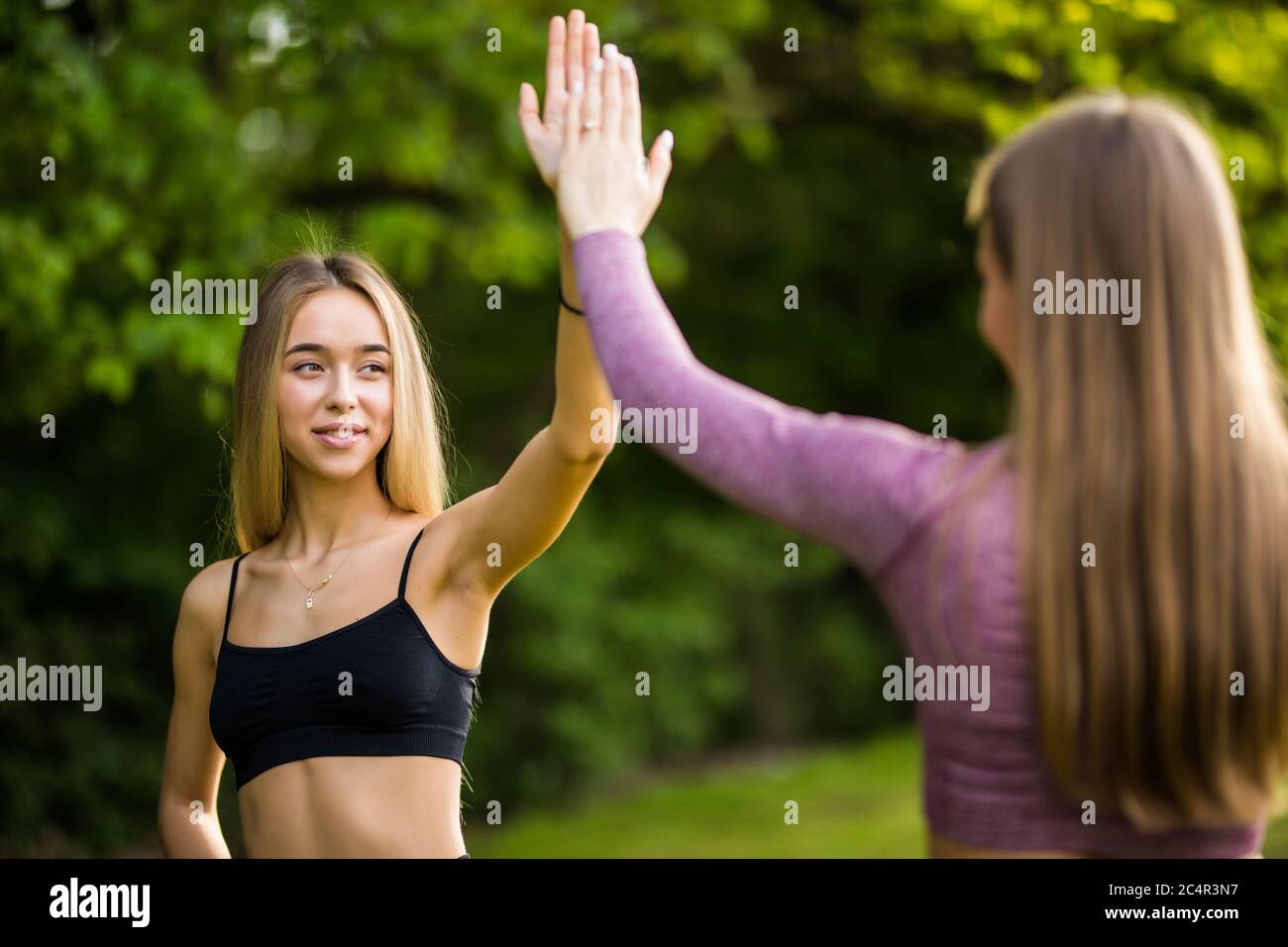 Two young sporty women giving each other a high five before workout ...
