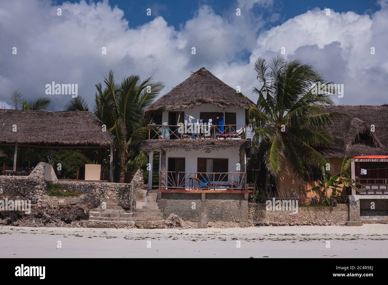 A beachfront property on Jambiani Beach in Zanzibar, Tanzania as a man takes a walk on the beach in the foreground Stock Photo