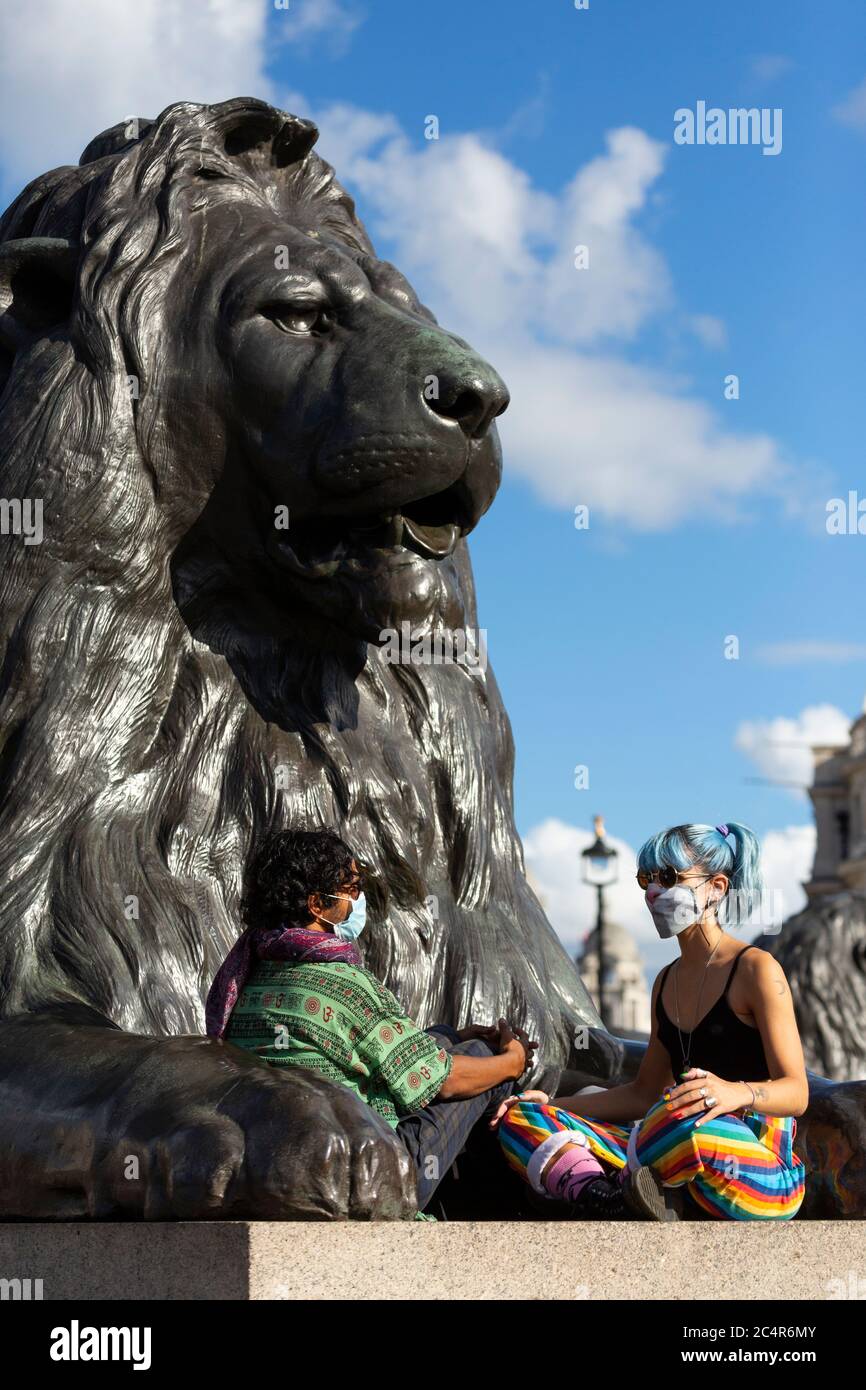 Protesters take a rest underneath a lion sculpture during a Black Lives Matter demonstration, Trafalgar Square, London, 20 June 2020 Stock Photo