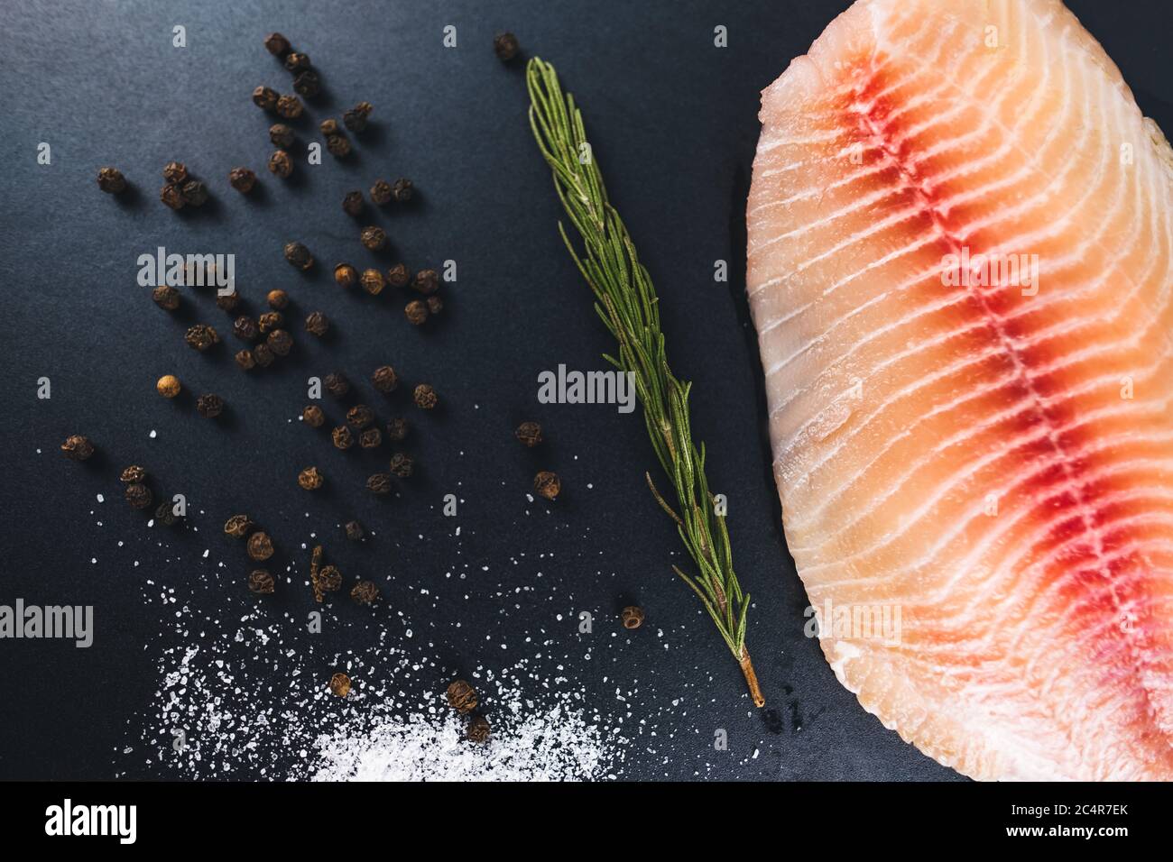 Fresh fillet of white tilapia fish laid out against a black background. Stock Photo