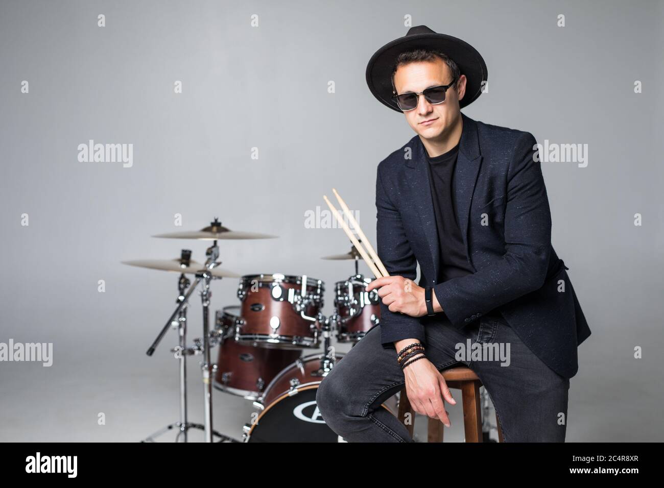 Young man drummer behind drum set and plays the drums in studio smiling Stock Photo