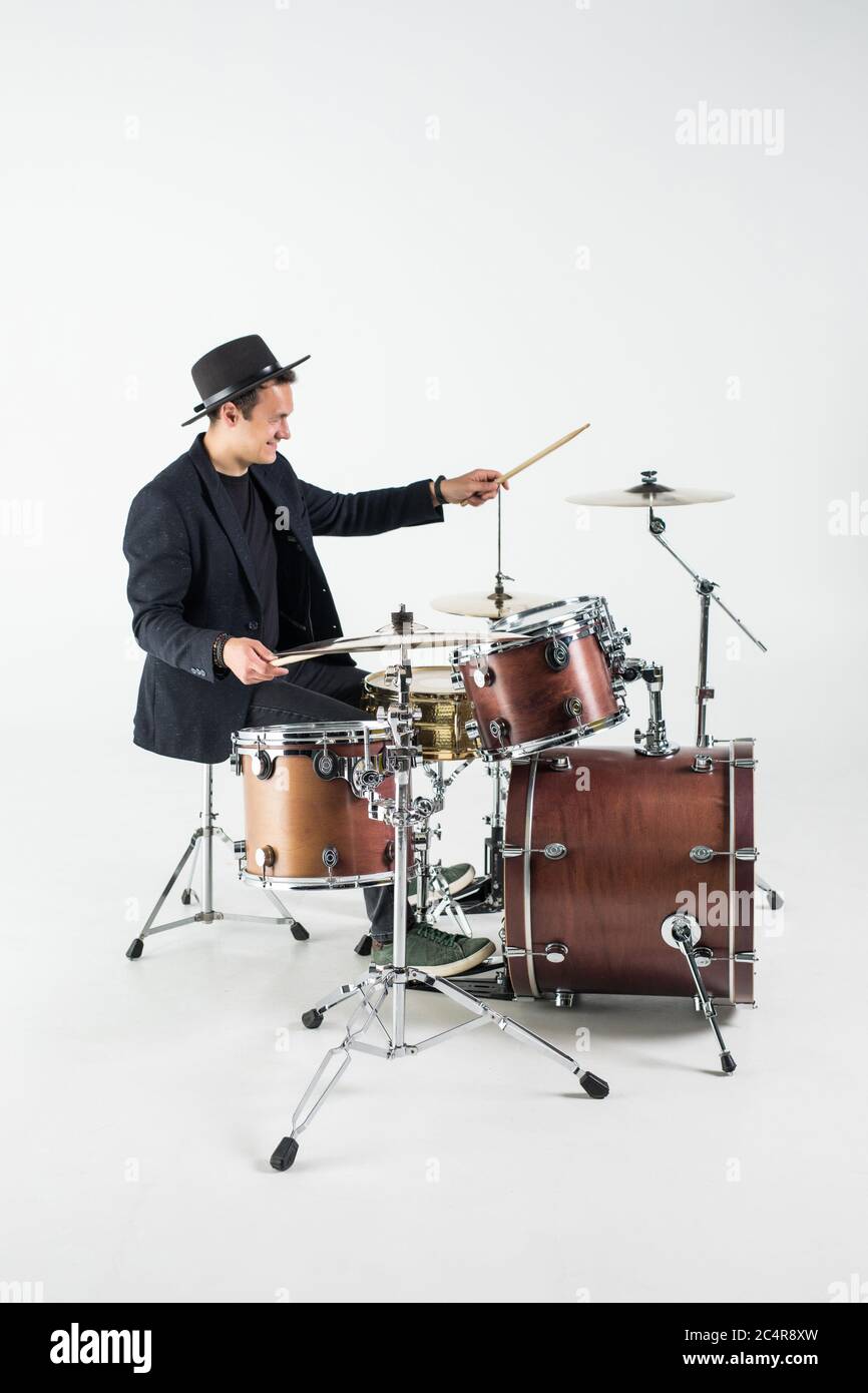 Young man drummer behind drum set and plays the drums in studio smiling Stock Photo