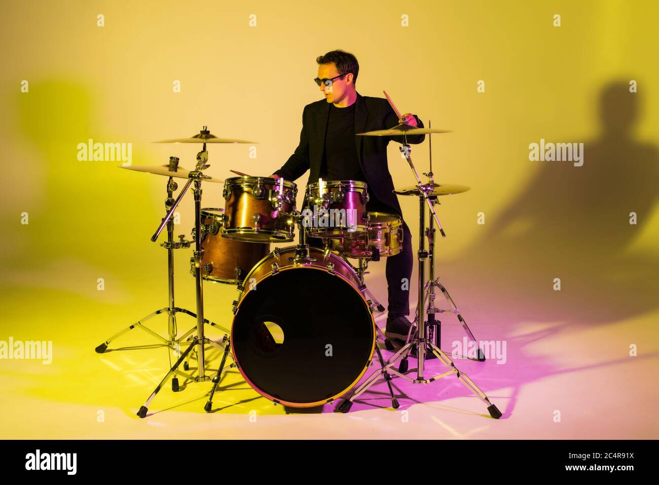 Caucasian male drummer improvising isolated on light studio background