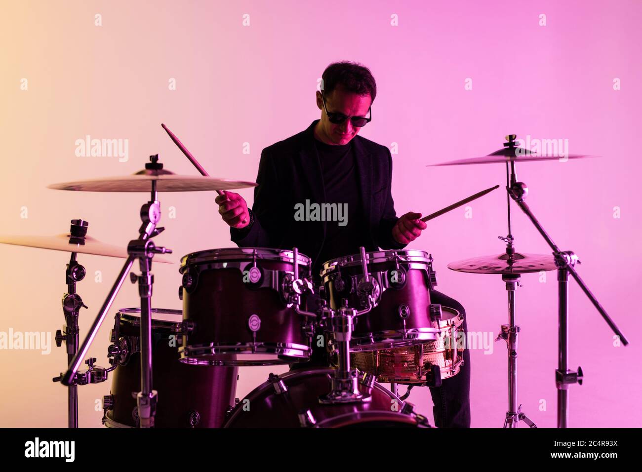 Caucasian male drummer improvising isolated on light studio background