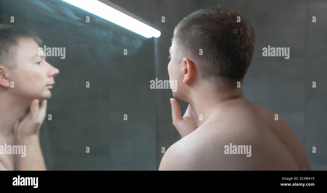 Guy looks in the mirror before shaving Stock Photo