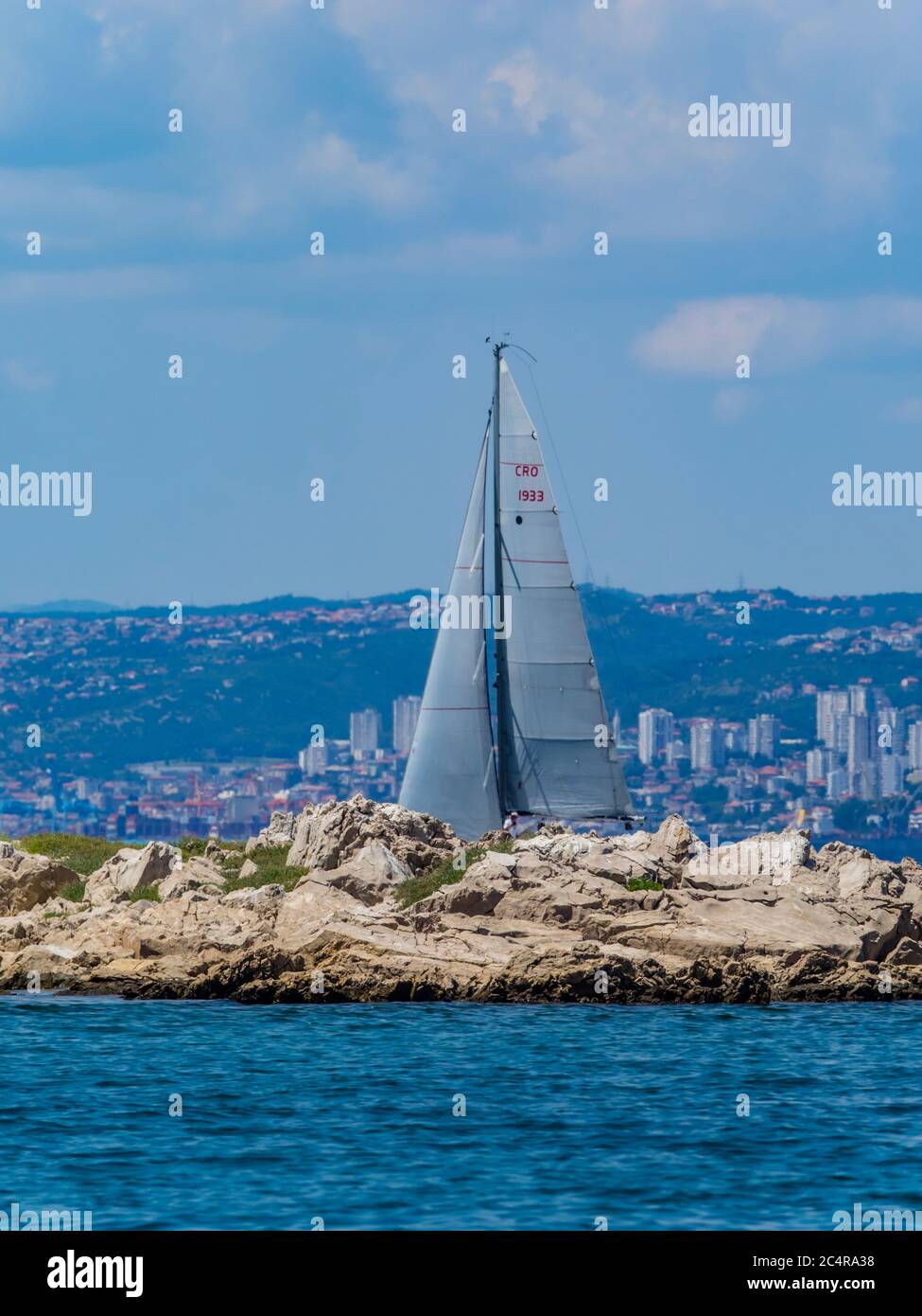 Sailboat vessel boat ship under sail behind small island near bridge Krk in Croatia Europe