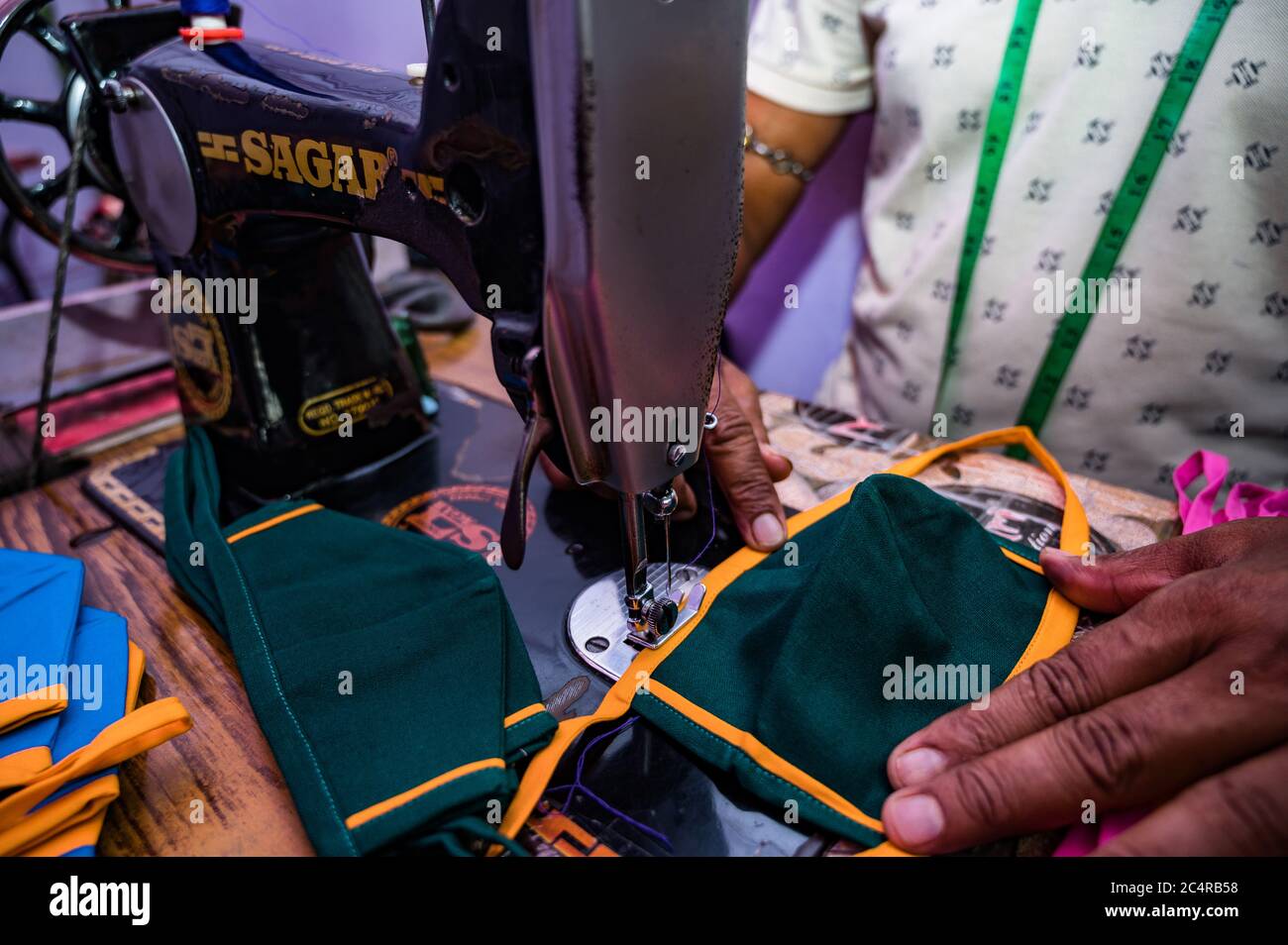 The lockdown was lifted in most places and the economy is slowly re-opening. A tailor prefers making masks than sewing cloths due to the financial cri Stock Photo