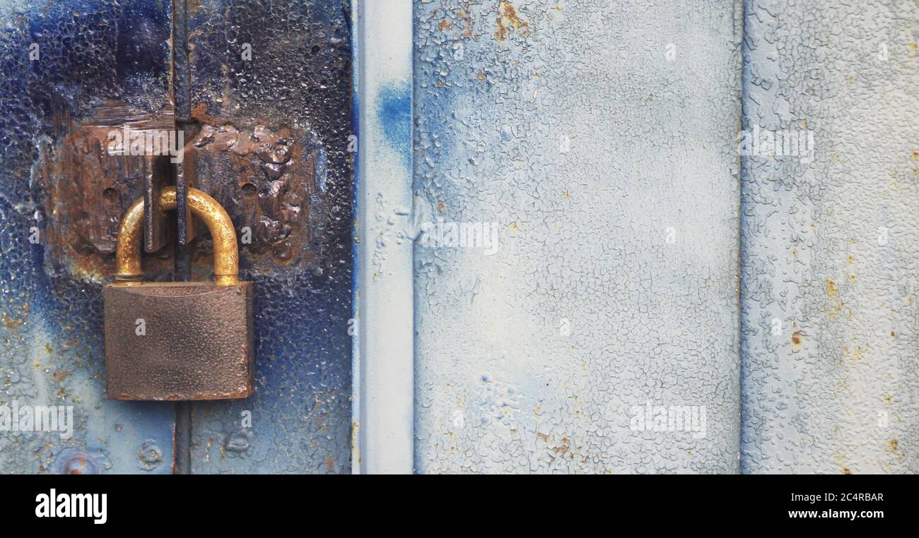 Old Lock hangs on a garage door with copyspace on the right. Locked