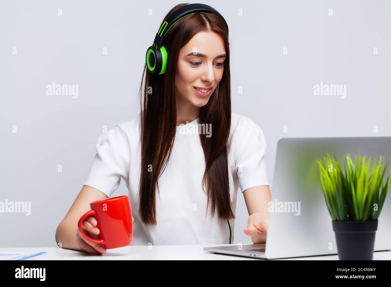 Beautiful young woman listening to music in headphones working on a ...
