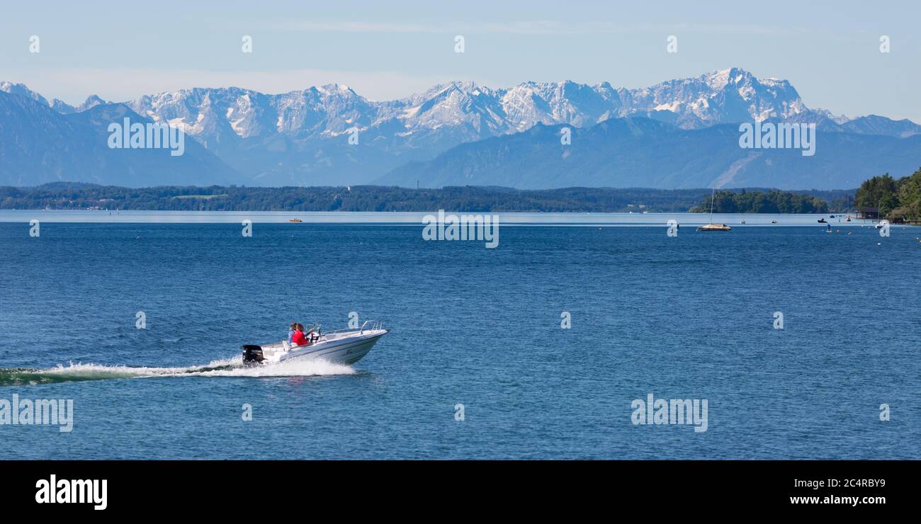 Motorboat cruising on Lake Starnberg. Snow capped alps with Zugspitze in the background. Stock Photo
