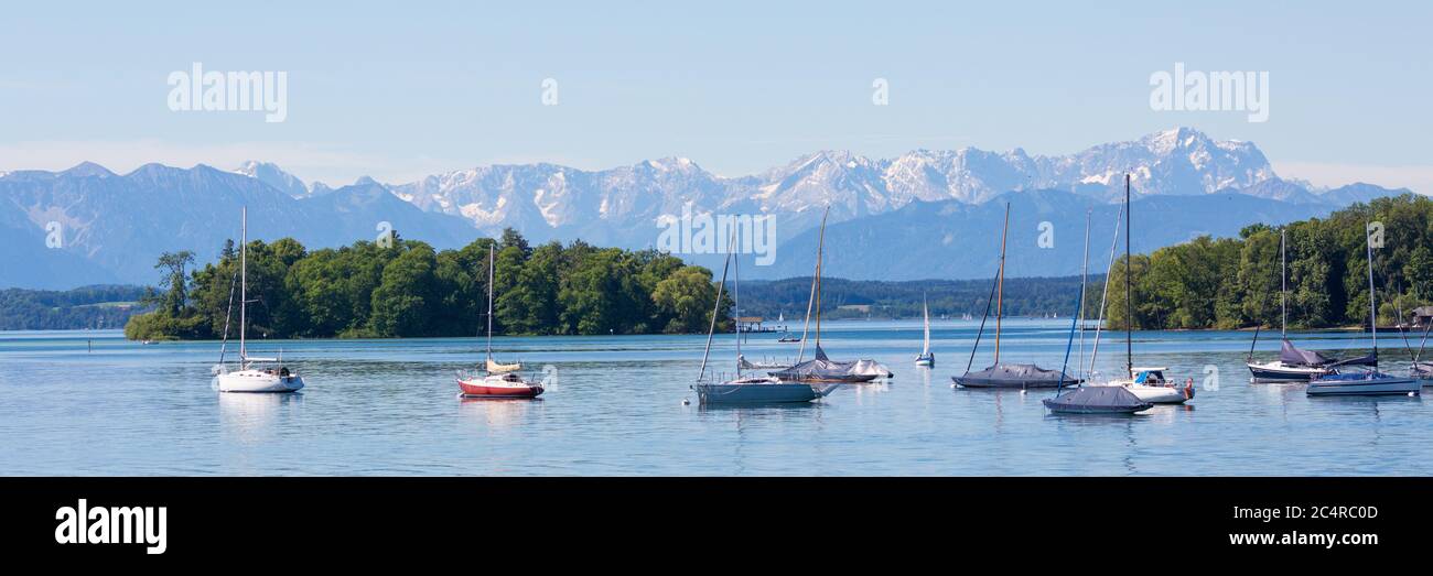 Panorama of Lake Starnberg with Roseninsel (rose island) and anchoring sailboats. Alps with Zugspitze at the horizon. Stock Photo