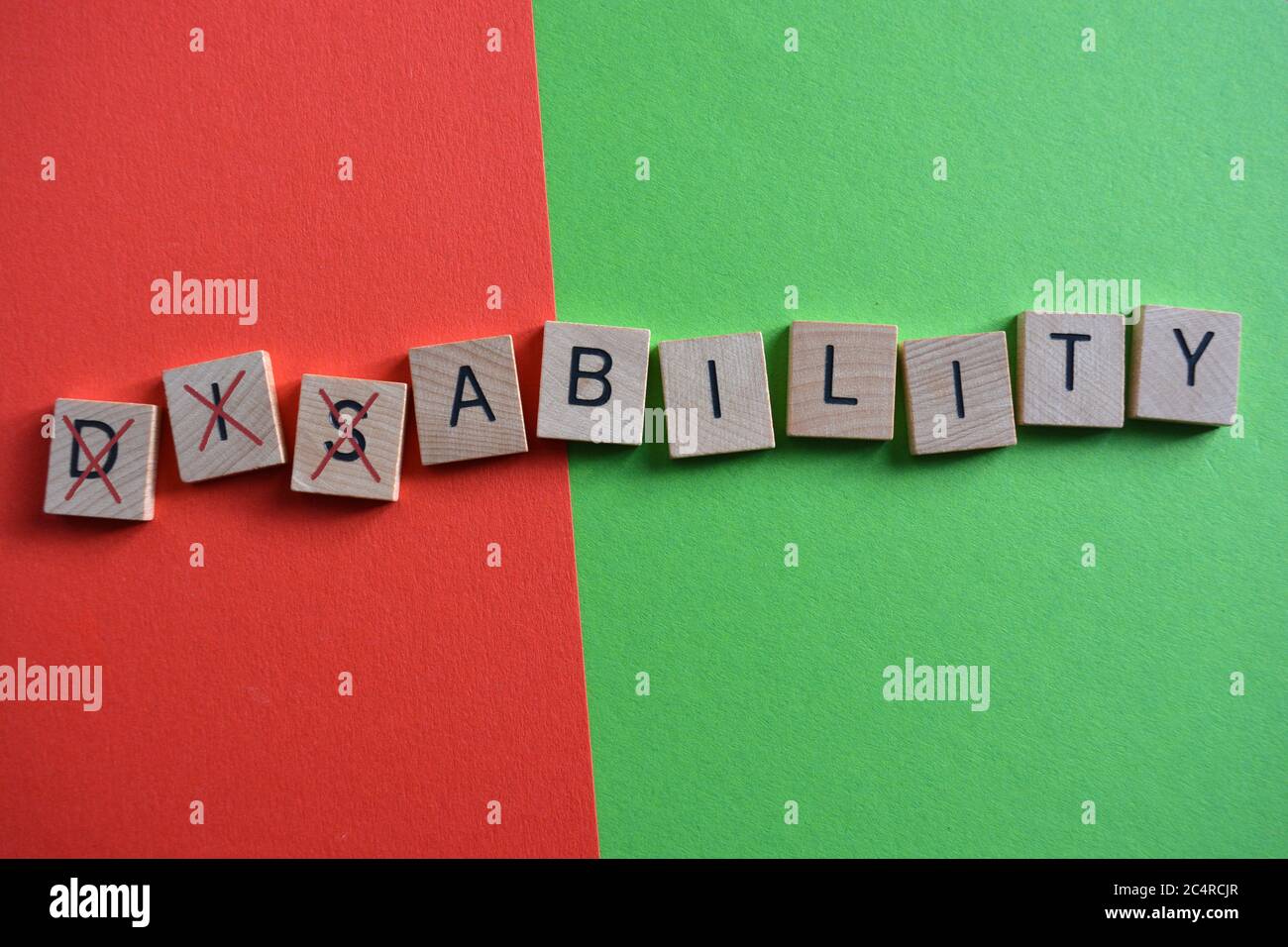 Disability, word in 3d wooden alphabet letters on a multi coloured background with Dis crossed out to leave the word Ability Stock Photo