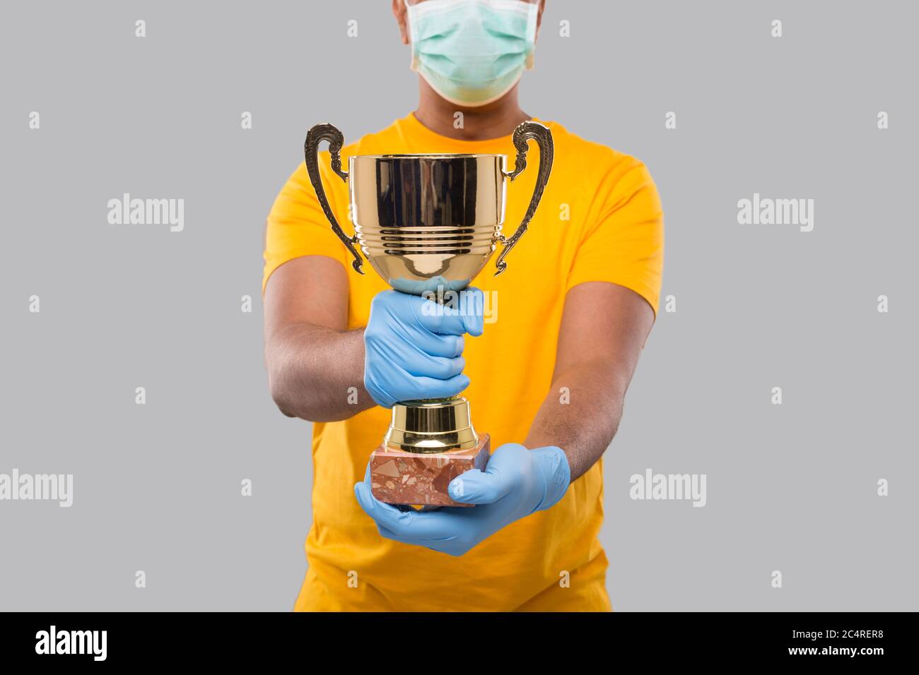 Indian Man Holding Trophy in Hands Wearing Medical Mask and Gloves Close Up Isolated Stock Photo
