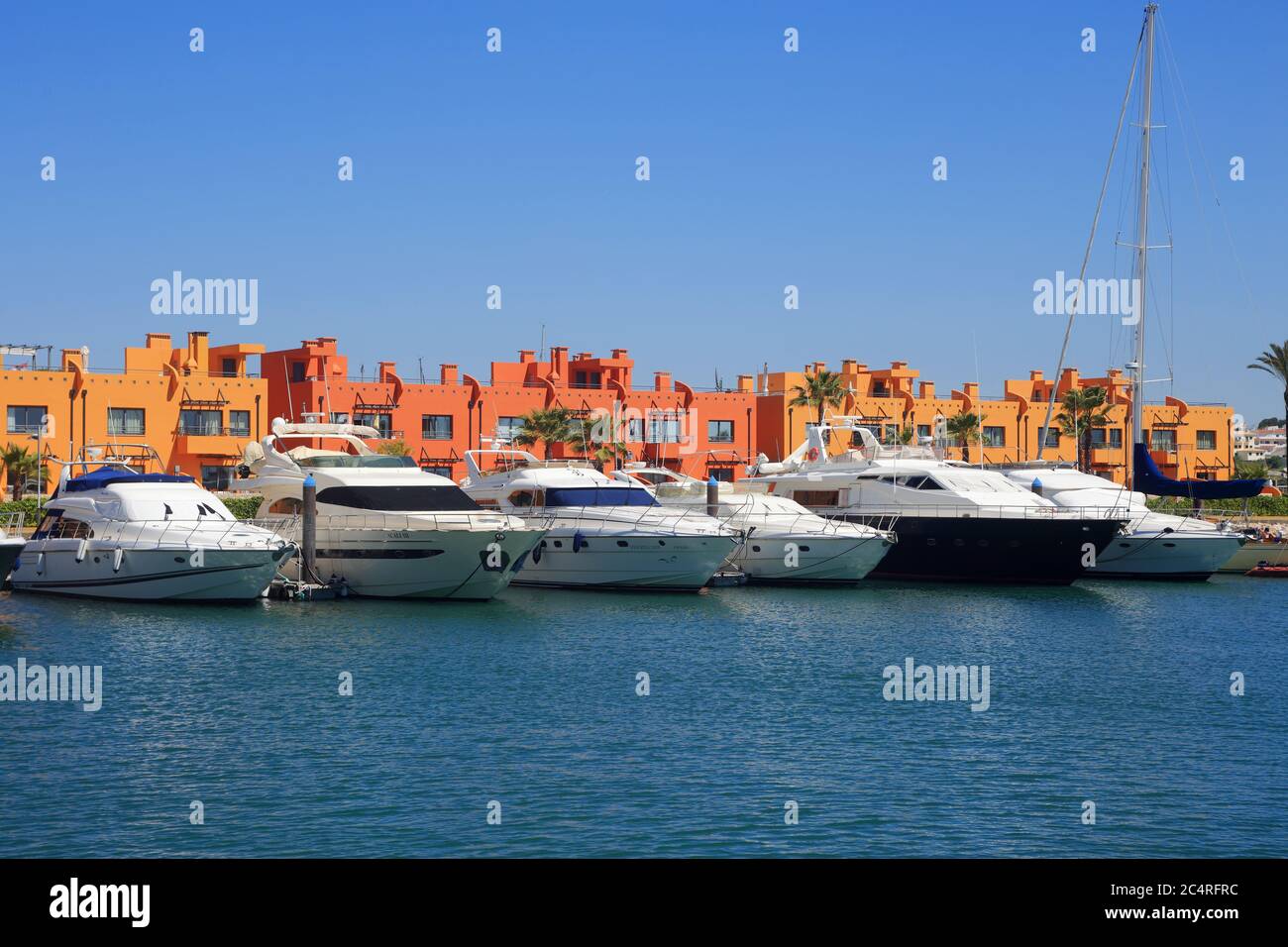 PORTIMAO, PORTUGAL. A row of luxury yachts berthed in front of colourful apartments in the Portimao Marina, located in the Algarve. Stock Photo