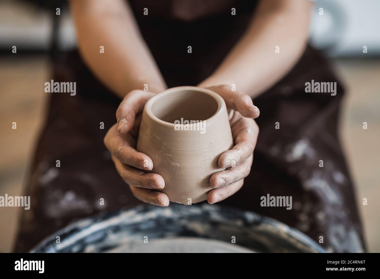 Cuts of product with wire. Craftsman hands making pottery bowl. Woman working on potter wheel. Family business shop sculpts pot from clay. Stock Photo