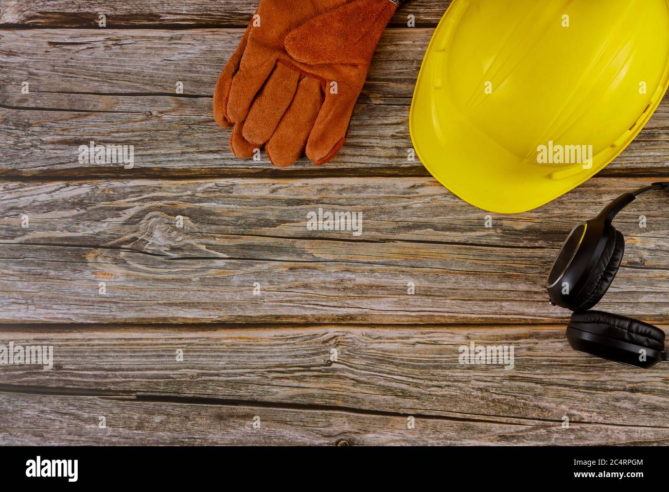 Protective workwear safety standard construction safety earmuffs leather safety helmet protective gloves on wooden table top view Stock Photo