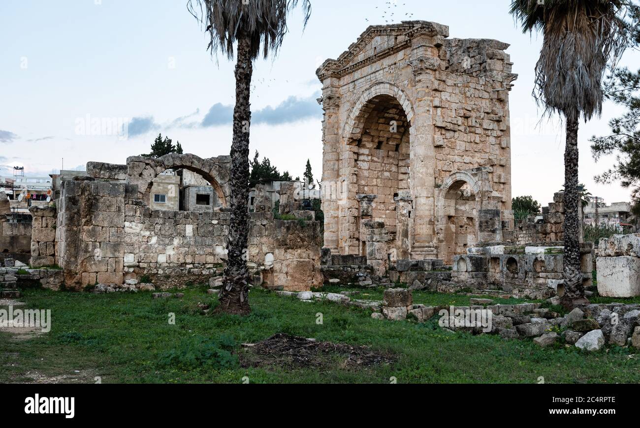 Monumental triumphal arch gate in Tyre Roman hippodrome, with modern buildings of Sour behind, Lebanon, Middle East Stock Photo