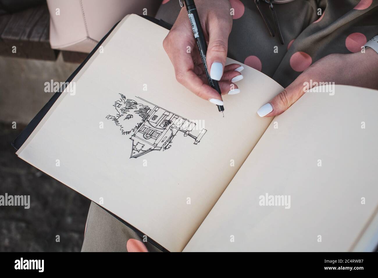 Sketchbook with a drawing of a house close-up. Girl draws in the fresh air. Stock Photo