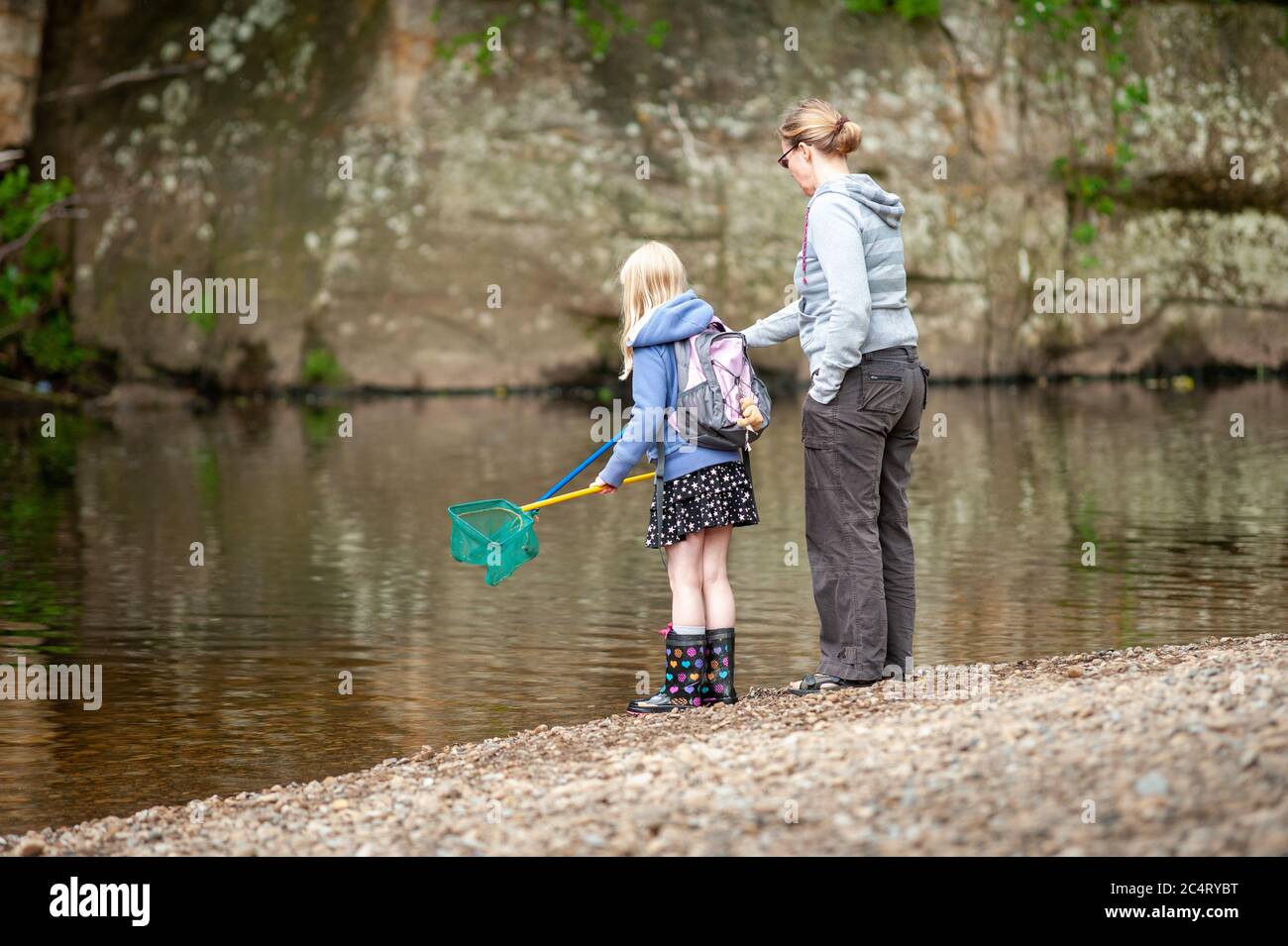 A Mother And Daughter With Fishing Nets At The Edge Of A River Stock a-mother-and-daughter-with-fishing-nets-at-the-edge-of-a-river-stock