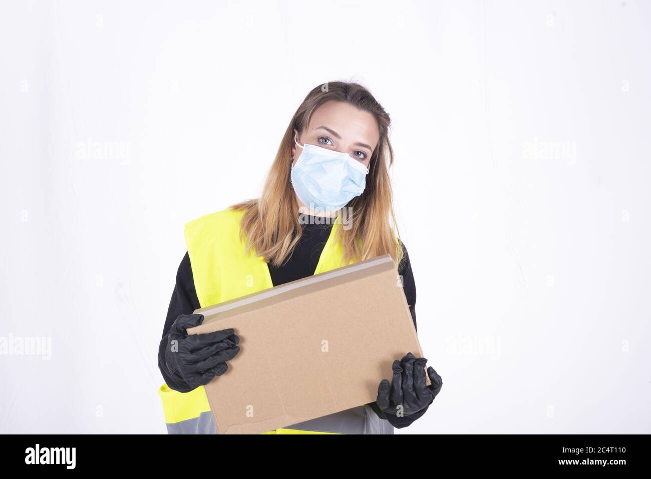 Female on a face mask and black plastic gloves holding a delivery box ...