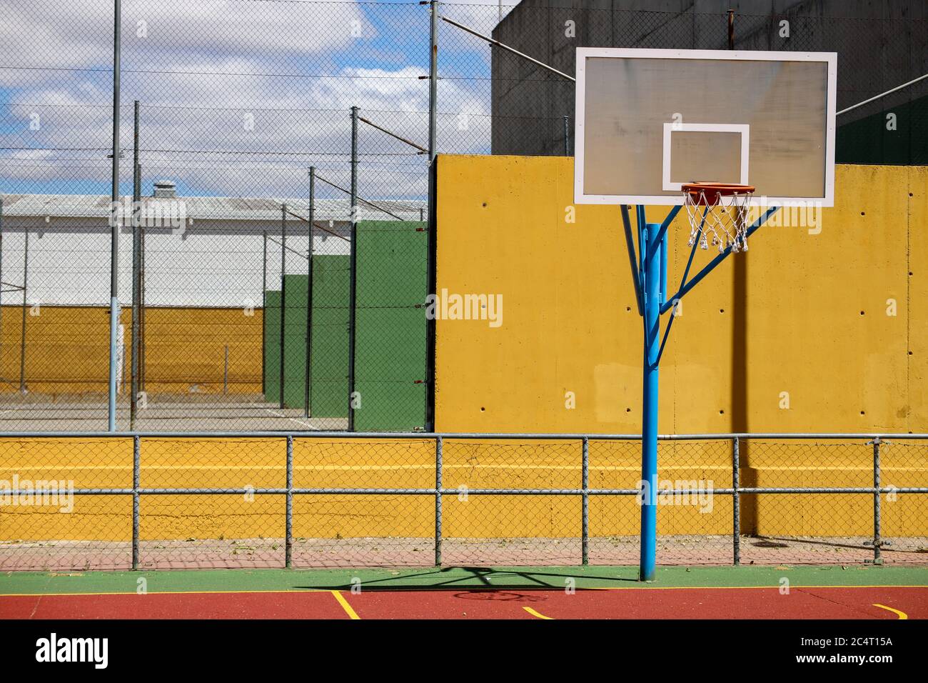 Basketball hoop surrounded by fences in a playground under the sunlight