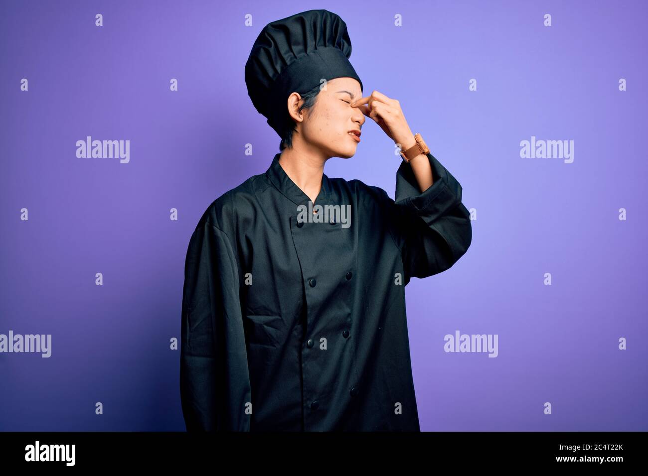 Young beautiful chinese chef woman wearing cooker uniform and hat over