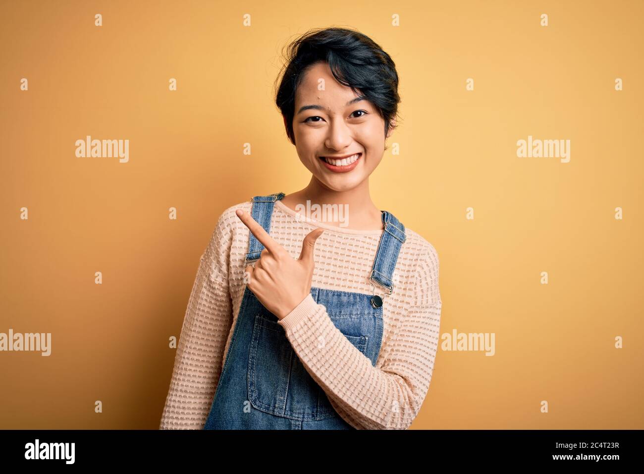Young beautiful asian girl wearing casual denim overalls over isolated ...