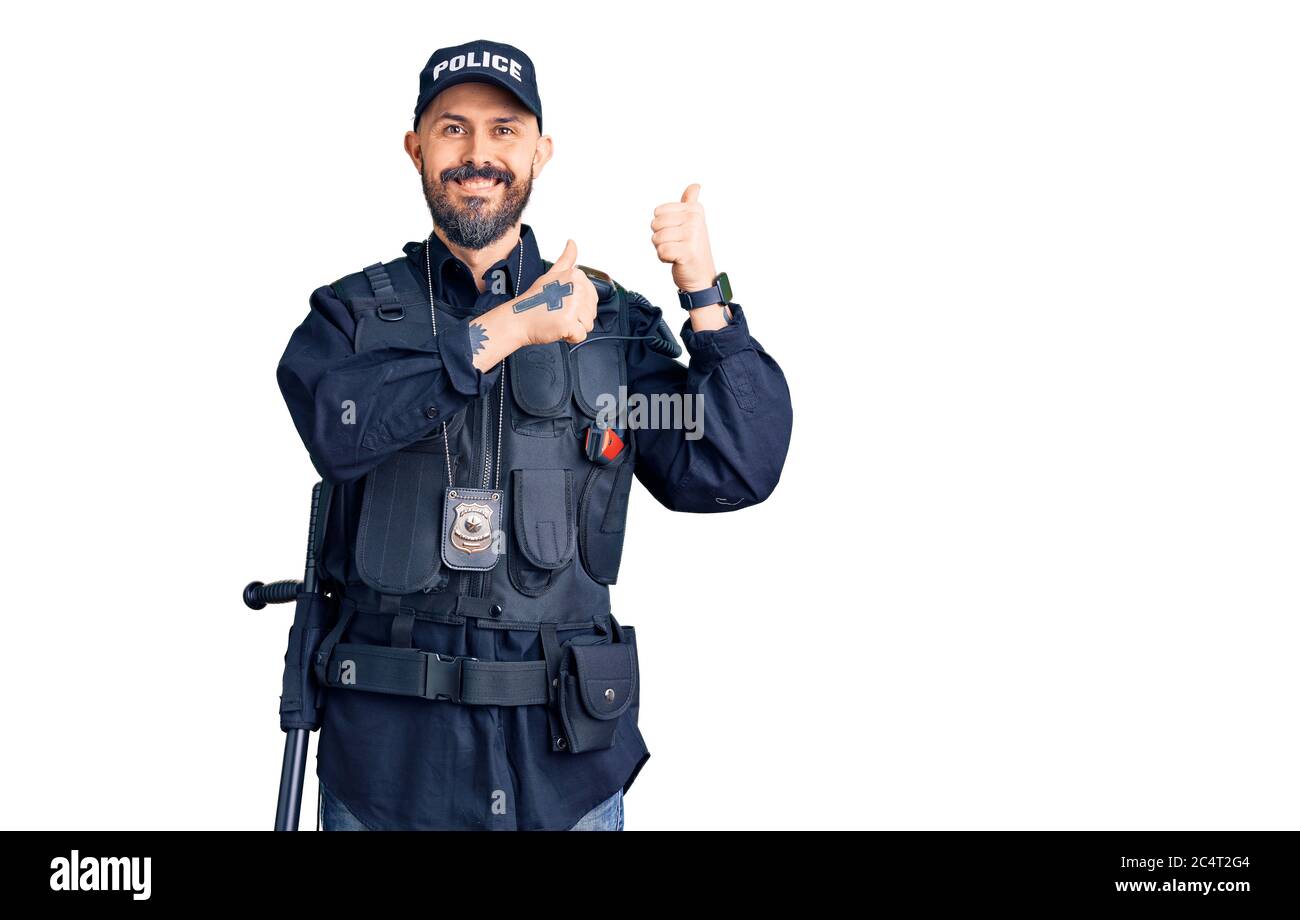 Young handsome man wearing police uniform pointing to the back behind with hand and thumbs up, smiling confident Stock Photo