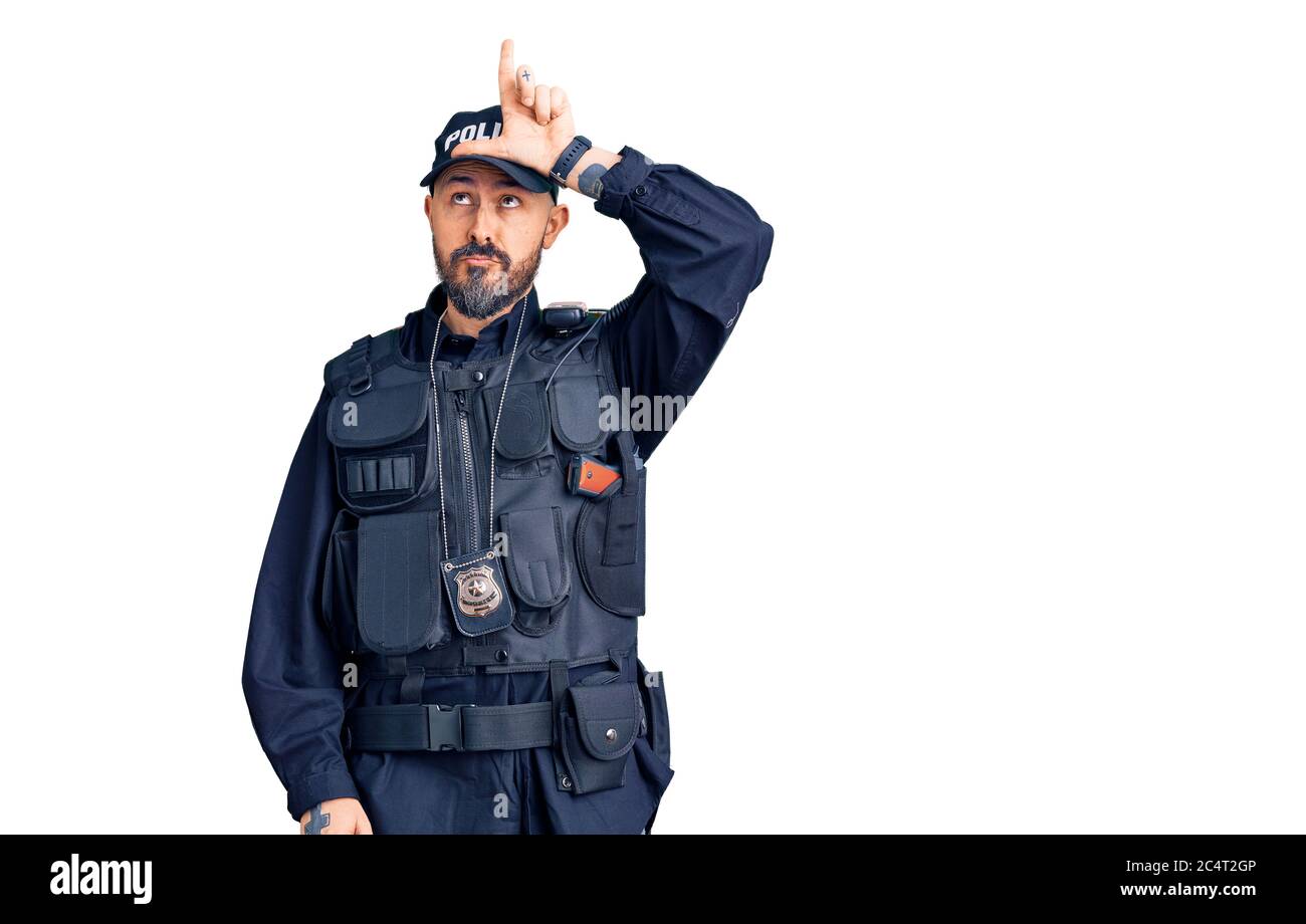 Young handsome man wearing police uniform making fun of people with fingers on forehead doing loser gesture mocking and insulting. Stock Photo
