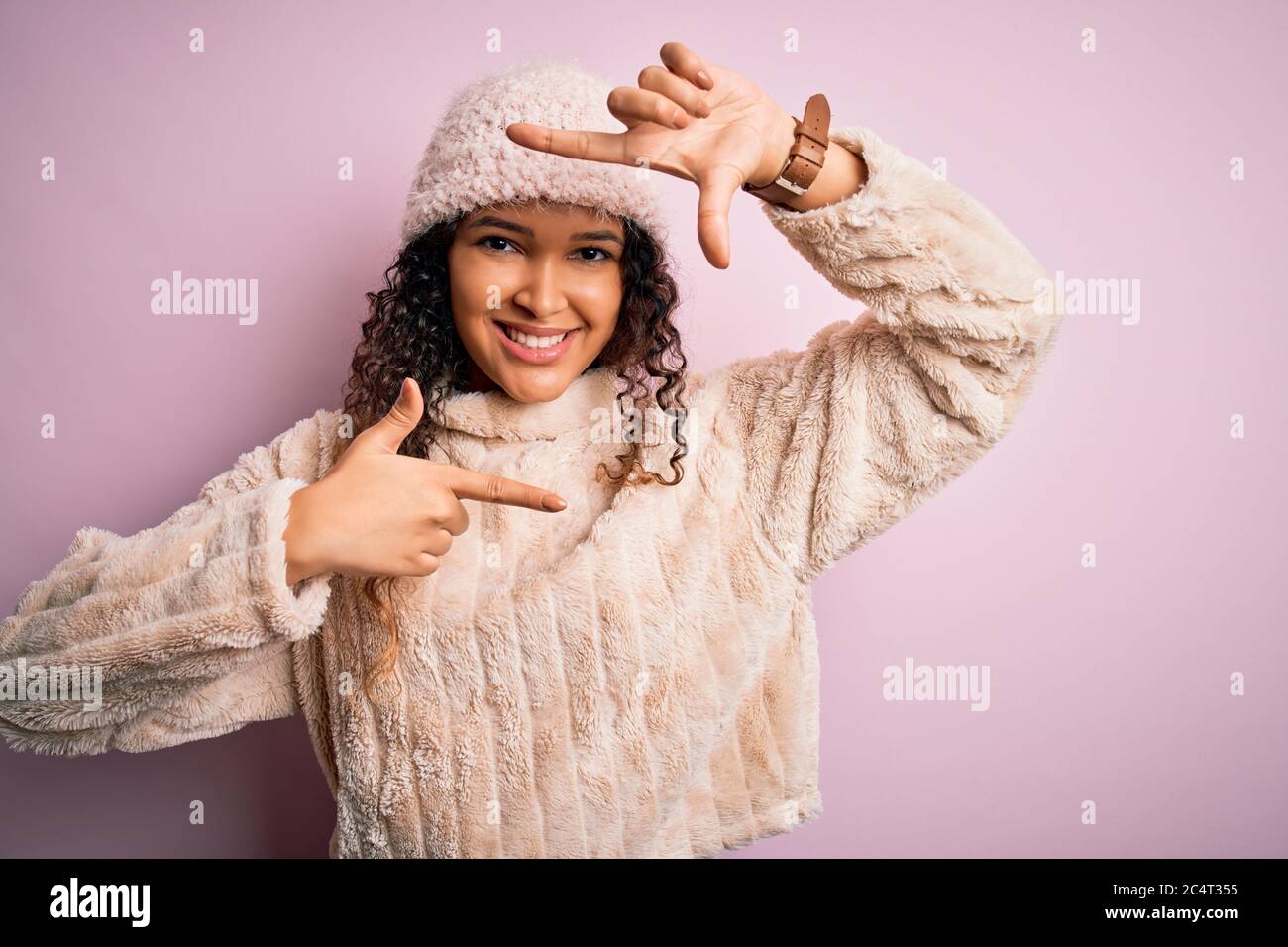 Beautiful woman with curly hair wearing casual sweater and wool cap ...