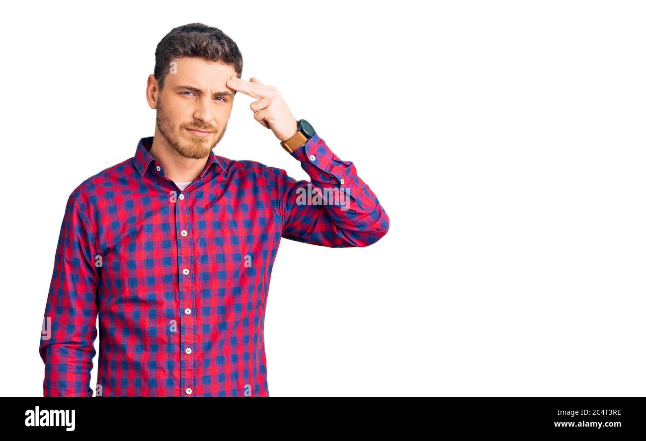 Handsome young man with bear wearing casual shirt pointing unhappy to pimple on forehead, ugly ...