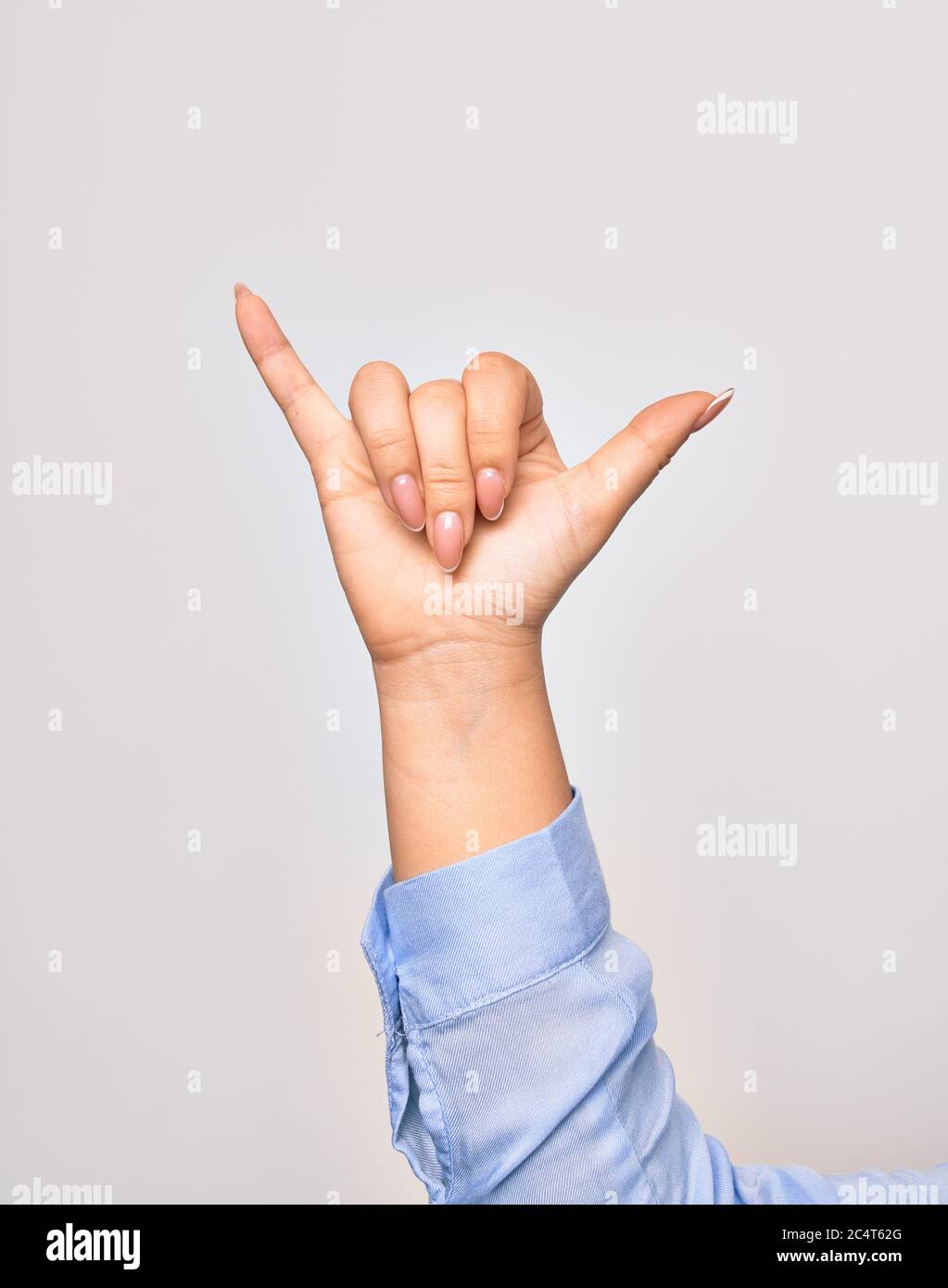 Hand of caucasian young woman doing surf salutation. Showing fingers doing telephone sign over isolated white background Stock Photo