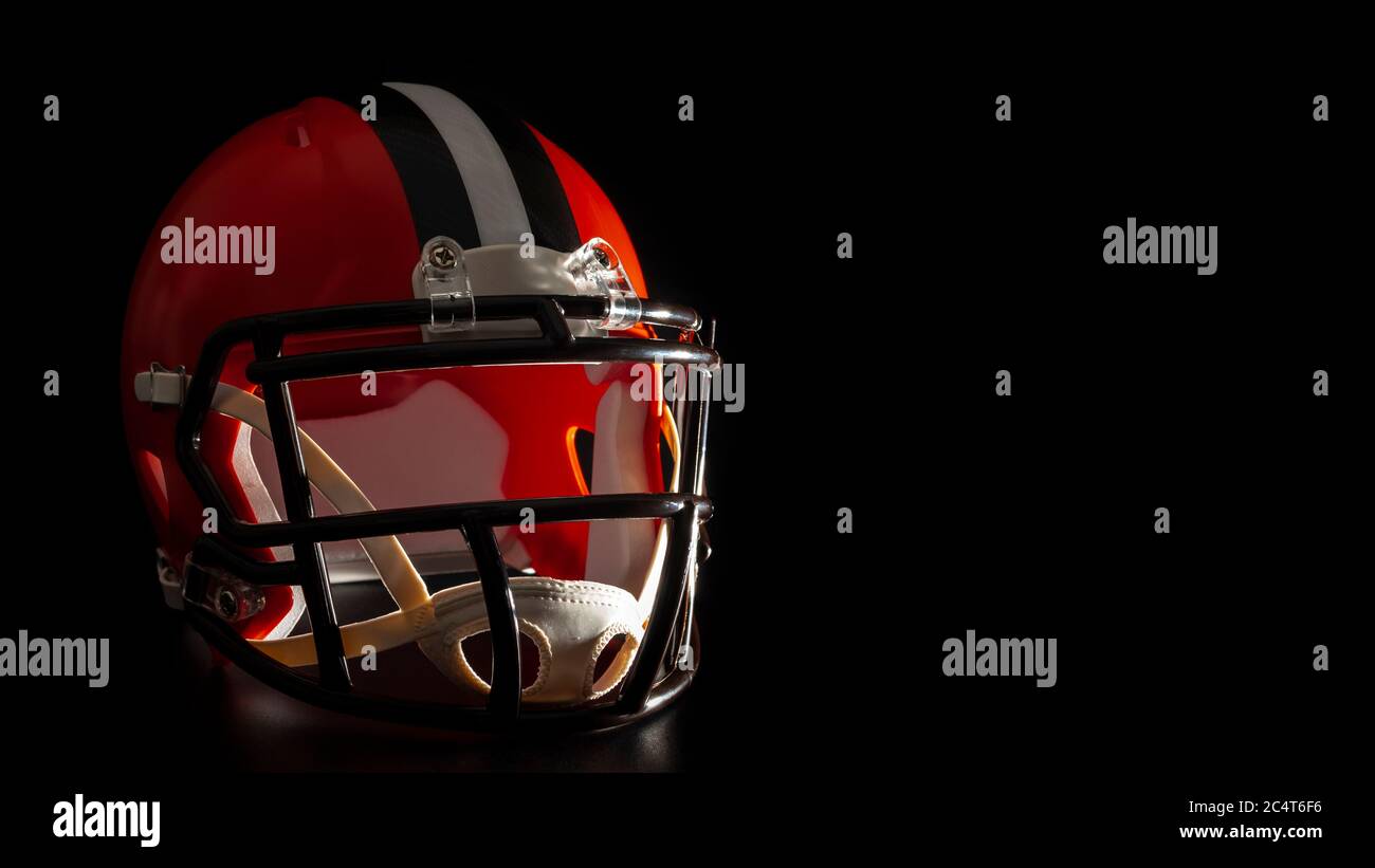 Dark side of college sports concept with high contrast lighting on american football helmet illuminated by dramatic hard light with harsh shadows isol Stock Photo