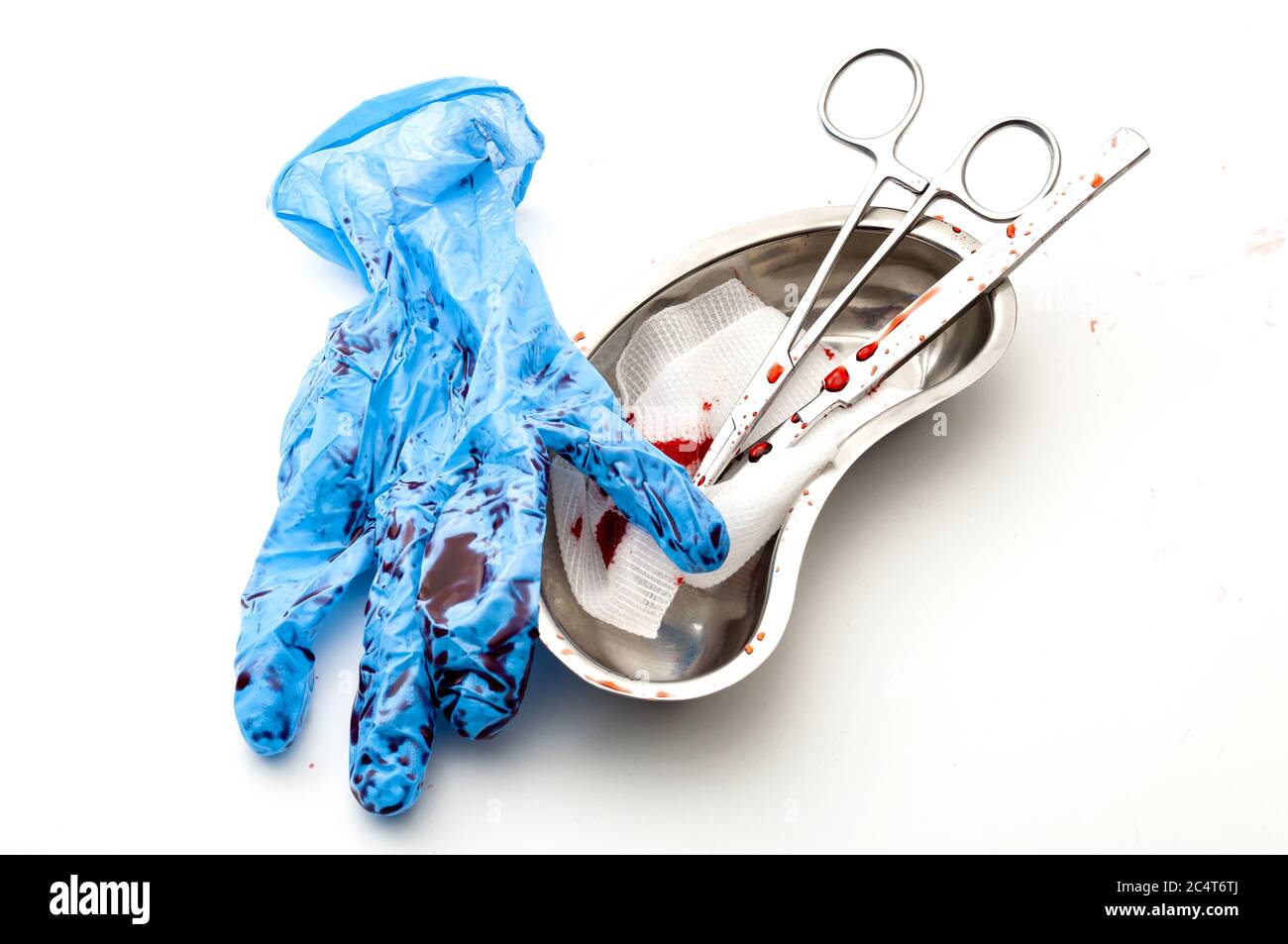 Surgery, bloody medical instruments and dirty operating room concept theme with scalpel, cotton swab, surgical scissors and latex gloves covered in bl Stock Photo