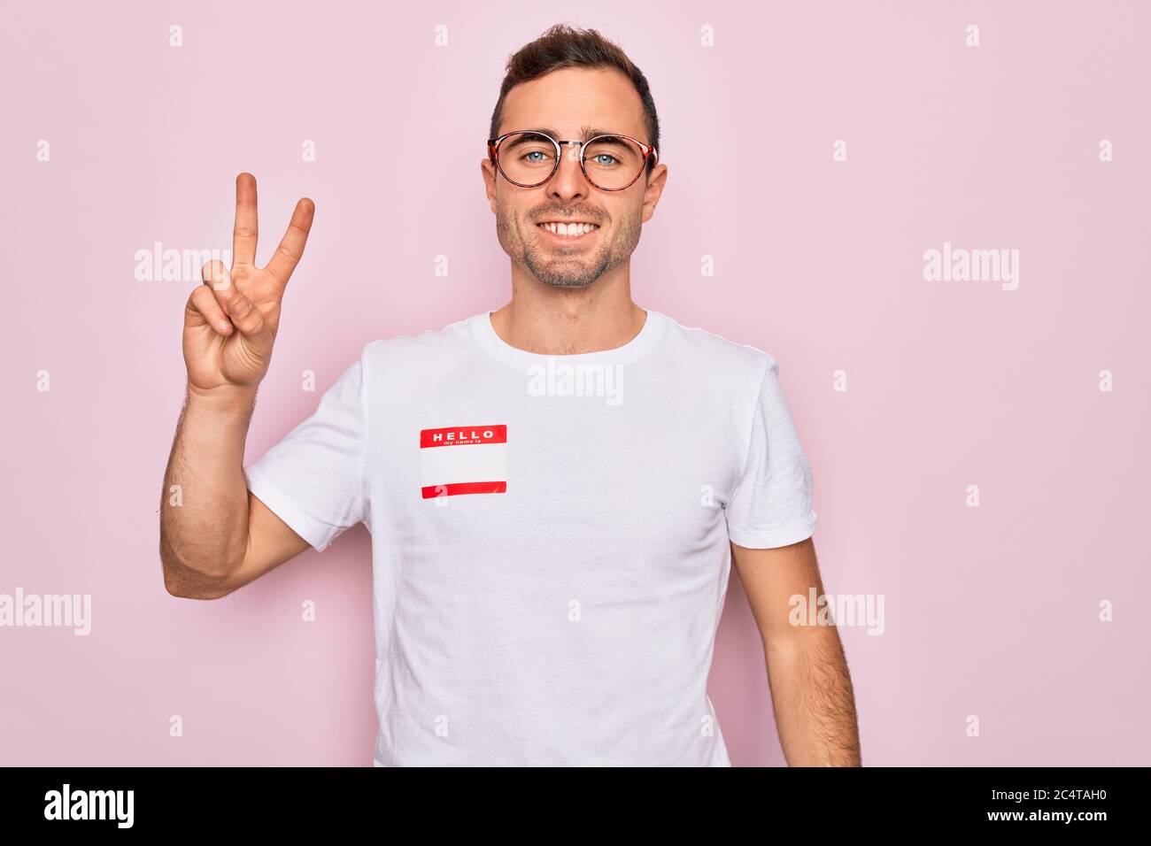 Handsome man with blue eyes wearing sticker with hello my name is ...