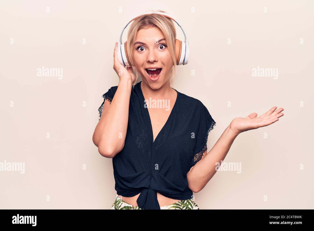 Young beautiful blonde woman listening to music using headphones over ...
