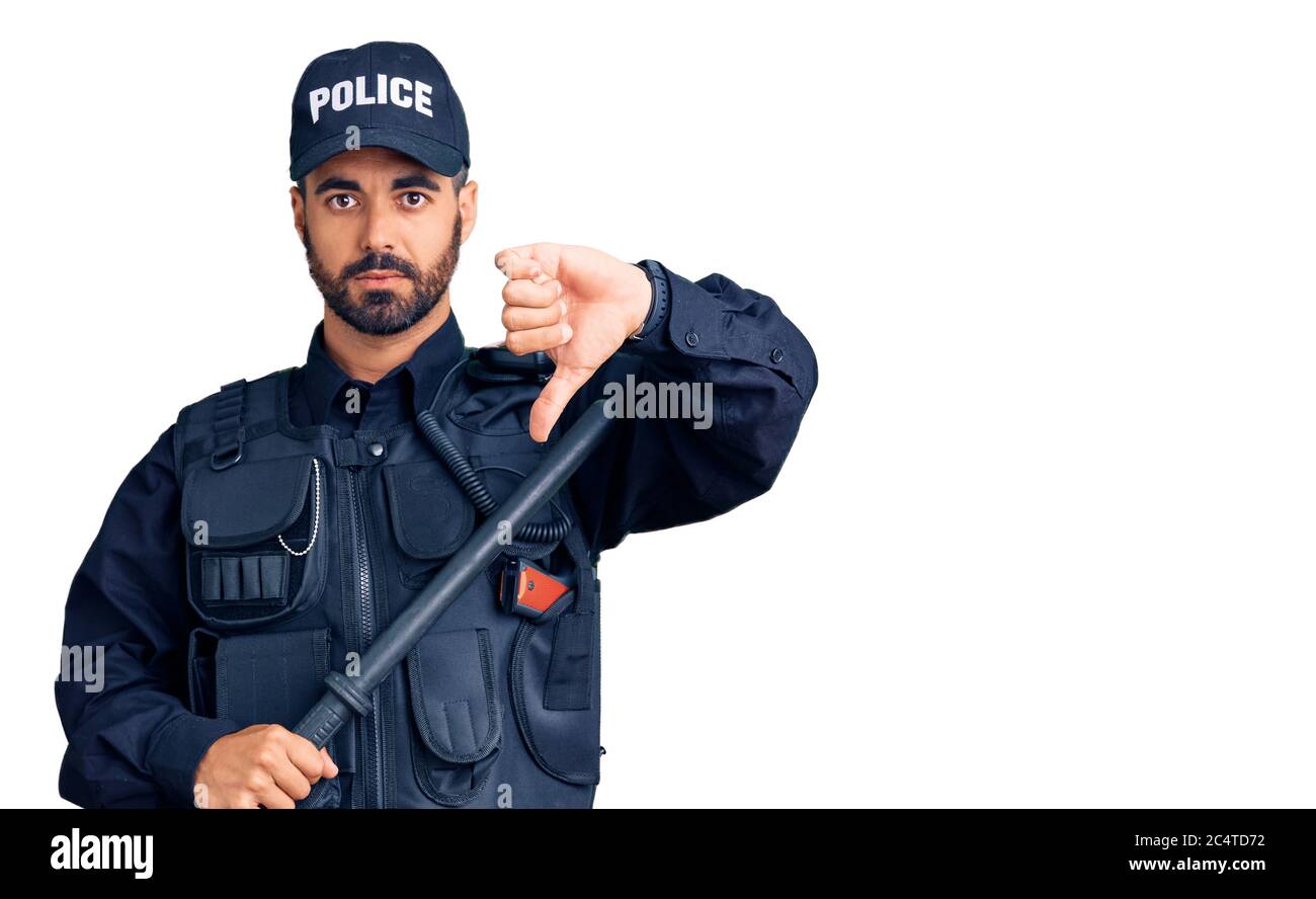 Young hispanic man wearing police uniform holding baton with angry face ...
