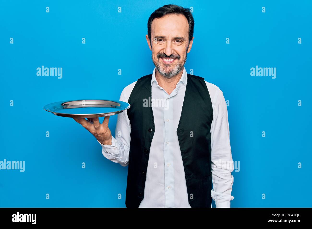 Waitressing Man Middle age handsome waitress man holding tray standing over isolated ...