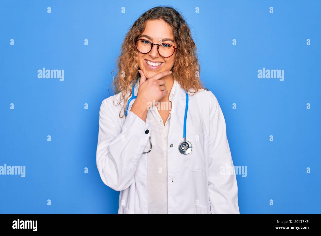 Young beautiful blonde doctor woman with blue eyes wearing coat and ...