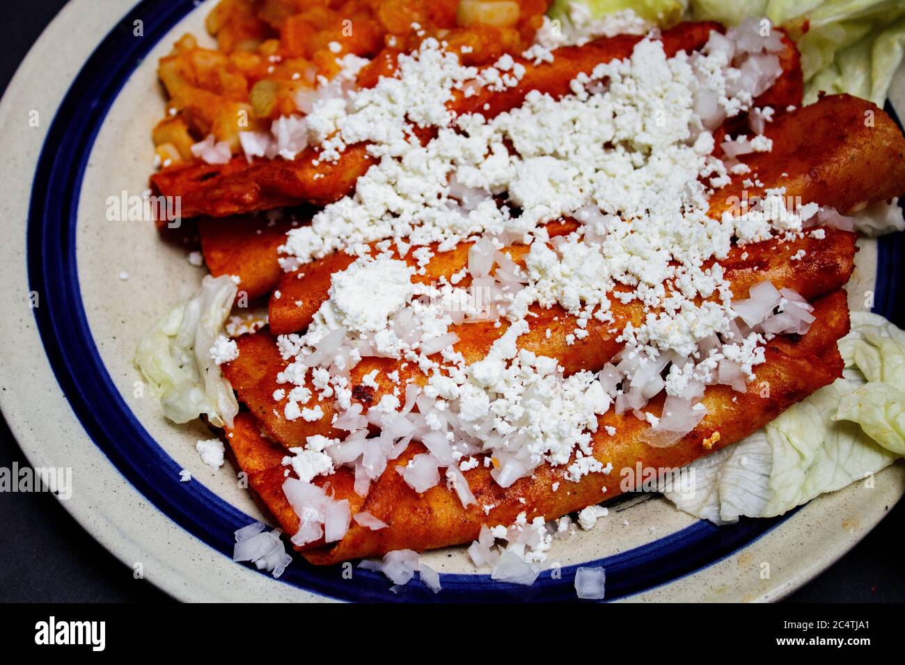 Mexican traditional dish Enchiladas with cheese potatoes lettuce cream