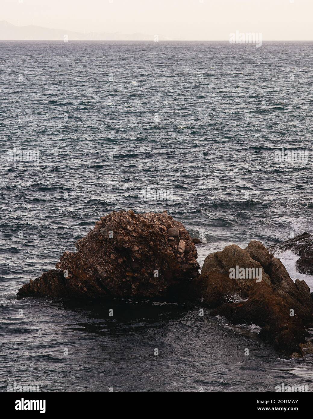 Big Rocks Visual Eos Vertical shot of big rocks in the blue sea during daylight Stock Photo ...