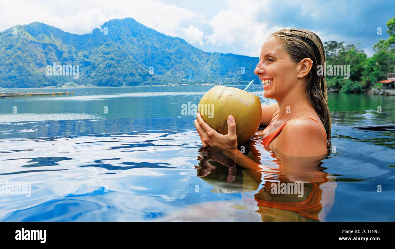 Active happy child have fun on summer beach holiday. Funny baby girl relaxing in infinity swimming pool with tropical jungle view. Healthy lifestyle Stock Photo