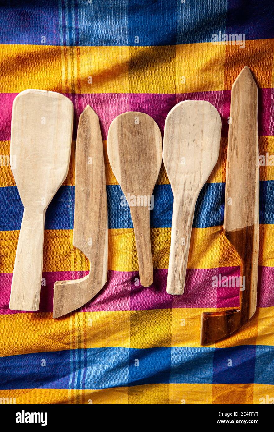 Village wooden cutlery set and kitchen tools on colourful asian style fabric background top view. Stock Photo