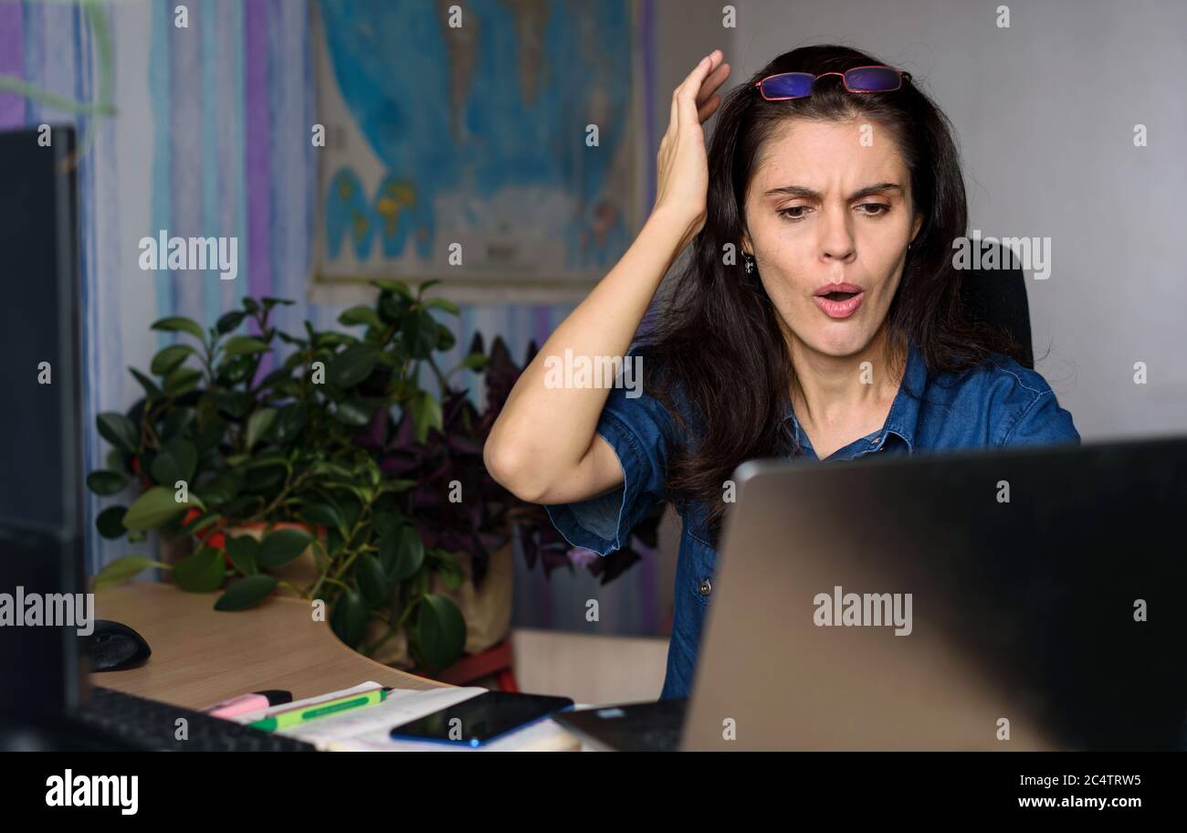 Shocked woman looking at laptop screen feel bad surprise annoyed reading online news frustrated with stuck computer problem website error sit at home Stock Photo