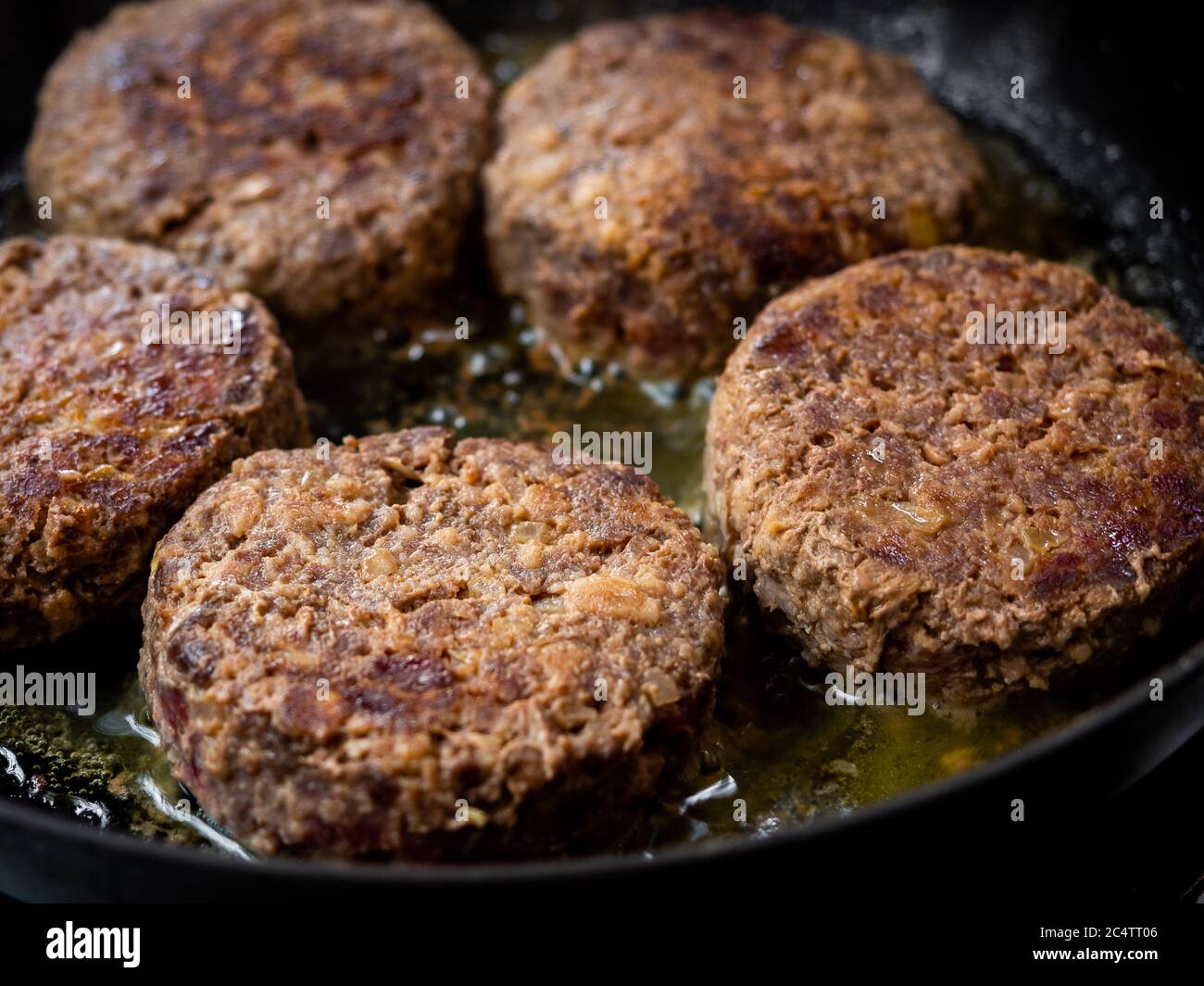 Beef burgers fried in frying pan. Close-up homemade juicy minced meat patties burgers in iron frying pan. Stock Photo