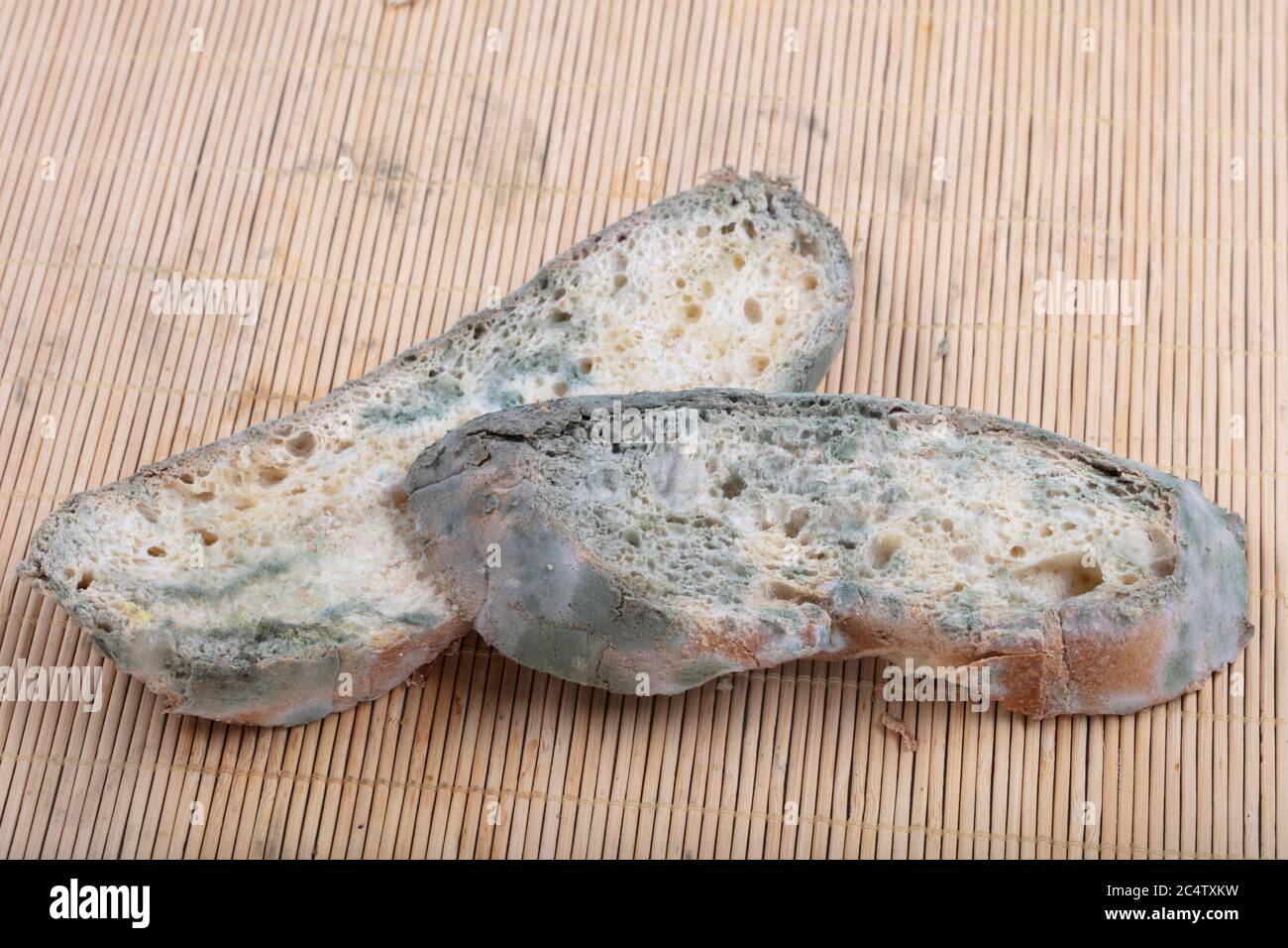Macrophotography of green mildew on a stale bread. Surface of moldy bread. Spoiled bread with mold. Moldy fungus on rotten bread. Top view. Stock Photo